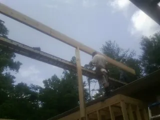 Carpenter setting a ridge beam over a new addition frame — Ice Dam Removal by Roofing Brothers in Spiceland