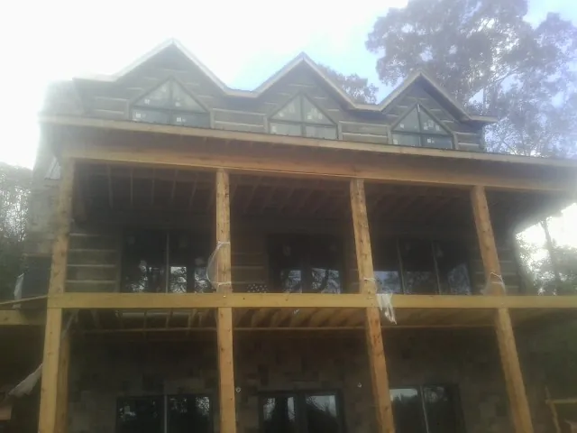 Dormers and porch framing on a large log home under construction — Roof Coating work by our crew in Spiceland
