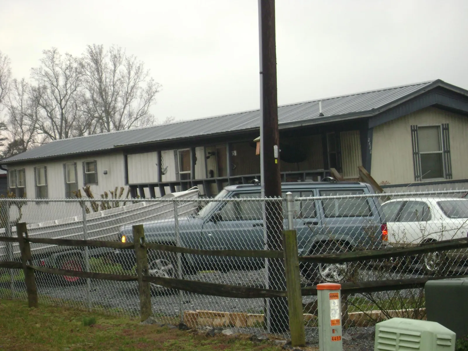 Dark metal roof on a long single story building behind a chain link fence in Spiceland