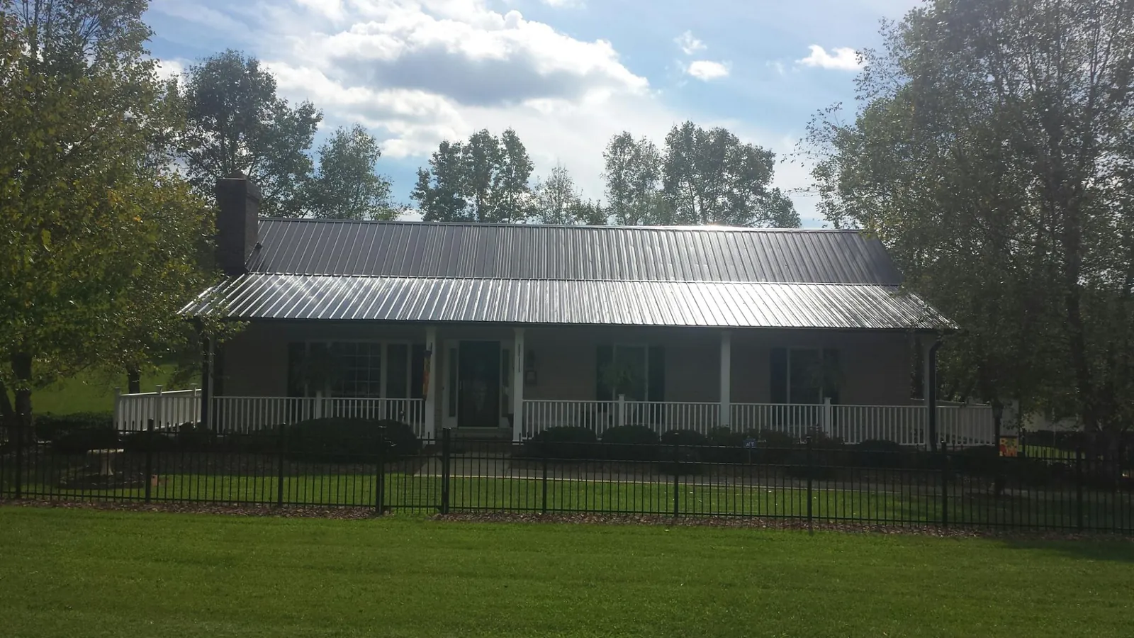 Gray metal roof on a brick ranch with a full width front porch — Gutter Guard Installation work by our crew in Spiceland