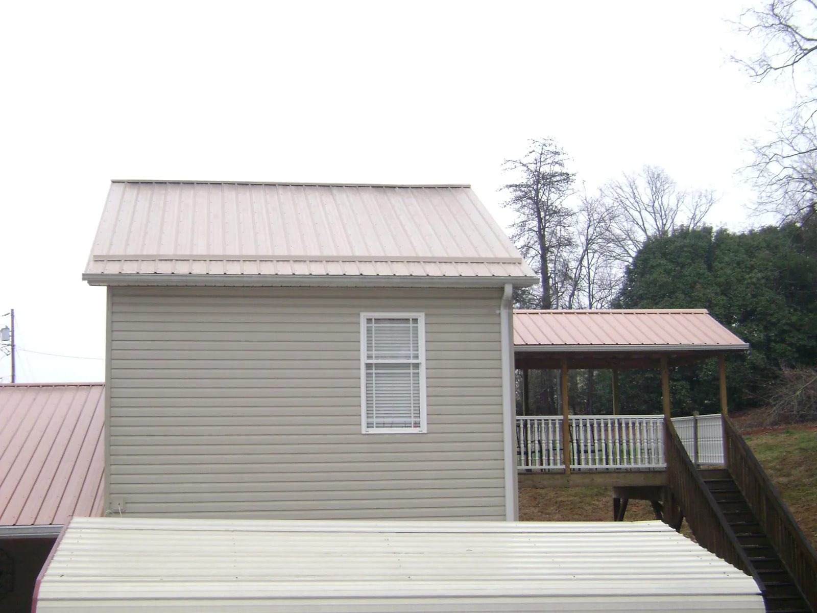 Tan metal roofs on a two story addition and attached porch, from a Roof Replacement job in Spiceland