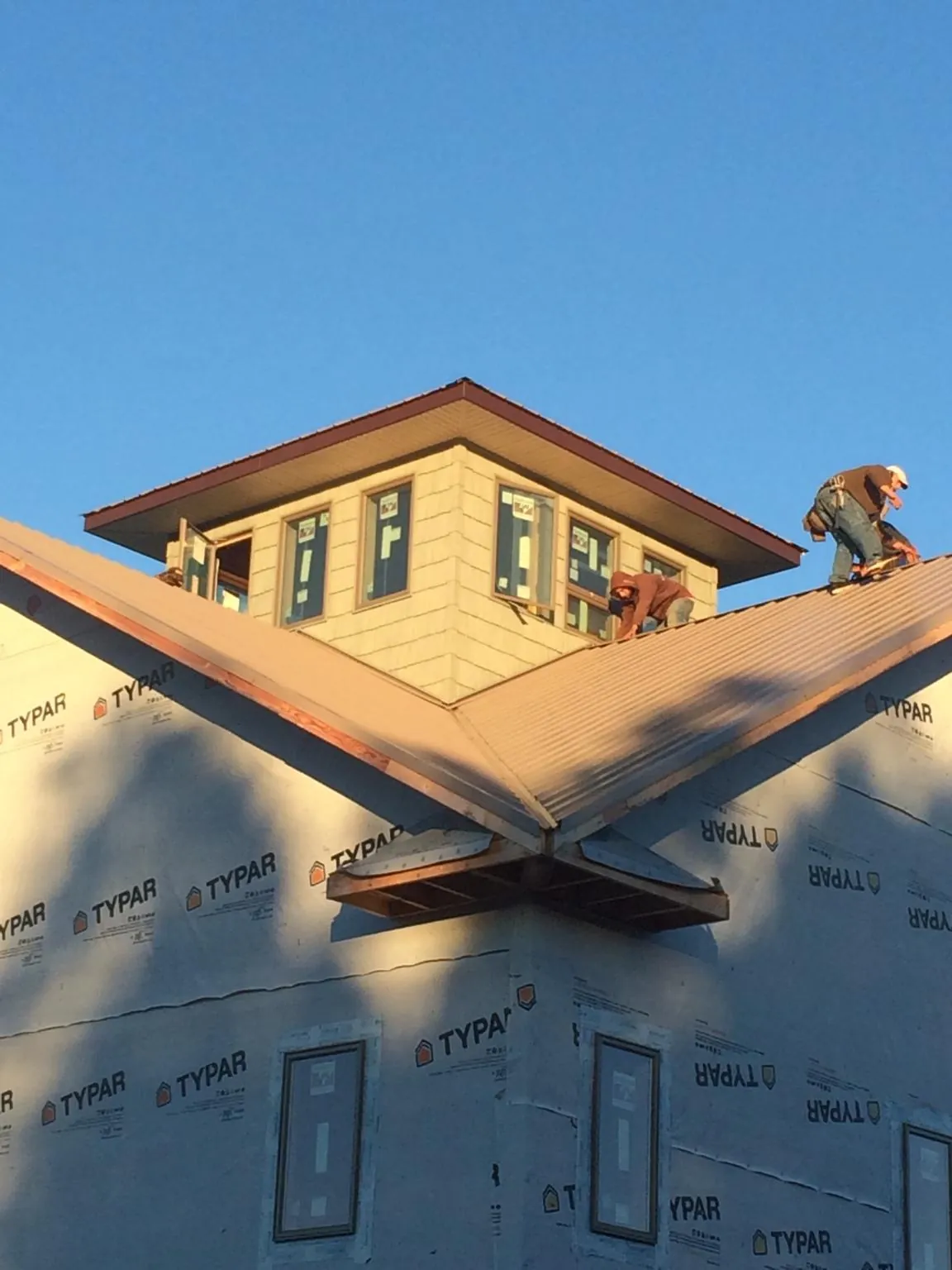 Roofers working around a rooftop cupola on a new metal roof at sunset — Roof Waterproofing in Spiceland by Roofing Brothers